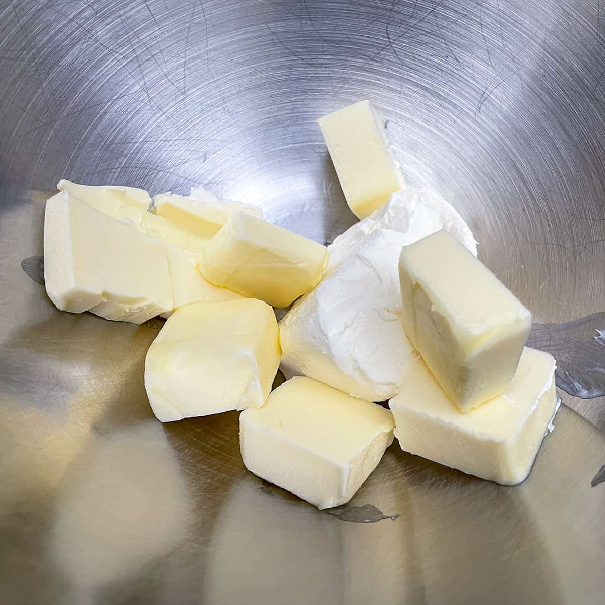 Cubed butter and a small block of cream cheese in the mixer bowl ready to be mixed.
