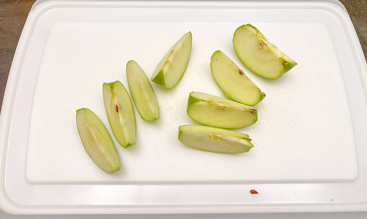Cutting an apple into eight segments on a cutting board.