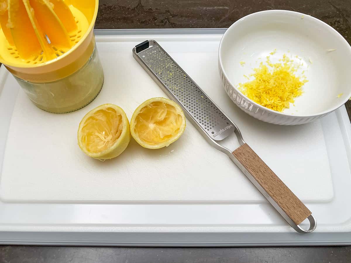 Zesting and juicing a lemon on a cutting board.