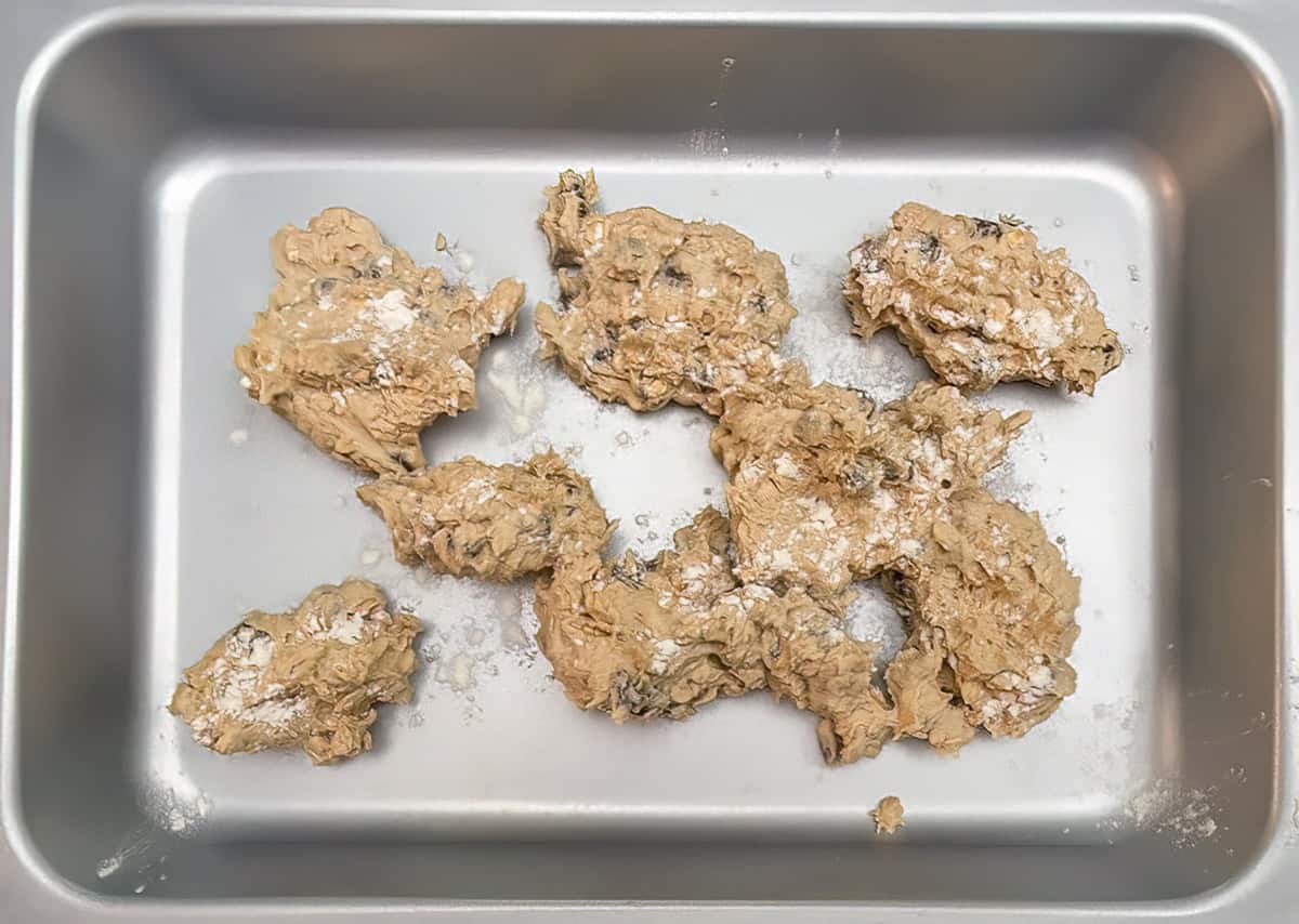 Adding cookie dough to the pan for making the bottom layer of the bars.