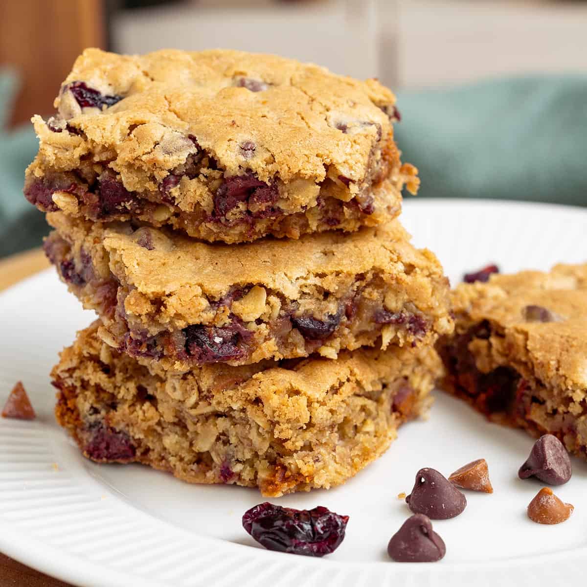 Cut cranberry cinnamon chocolate chip bars sitting stacked on a plate feature photo.