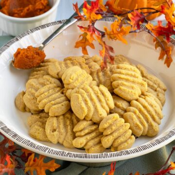A pie dish with a pile of pumpkin spreize cookie stacked in the dish.
