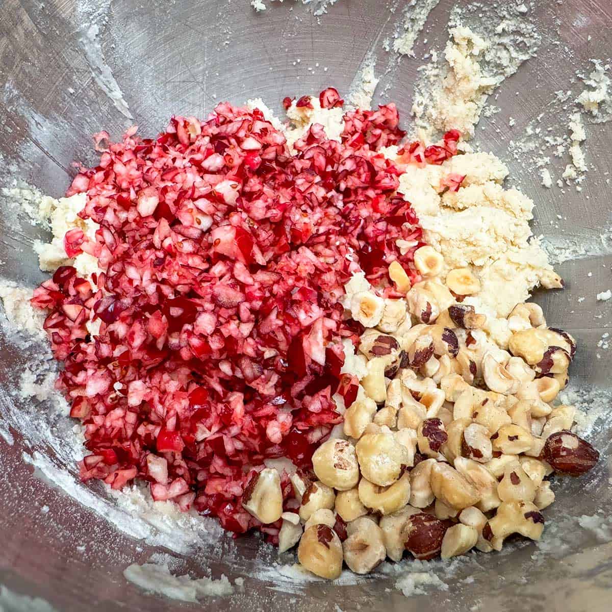 Adding chopped cranberries and hazelnuts to the cookie dough.