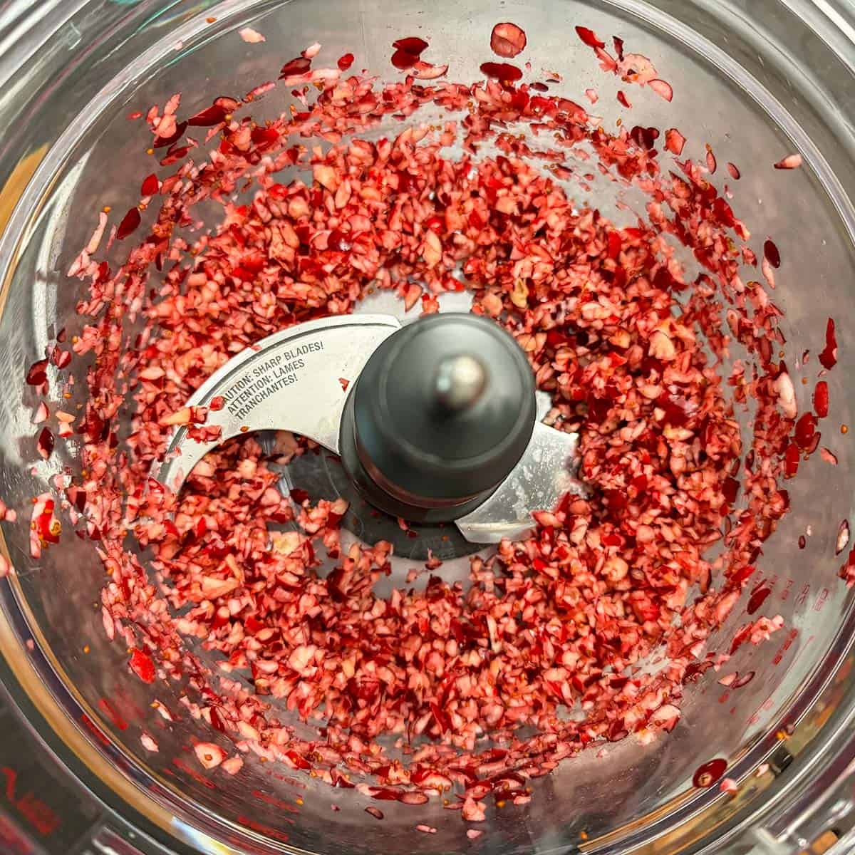 Chopped fresh cranberries in a food processor bowl.