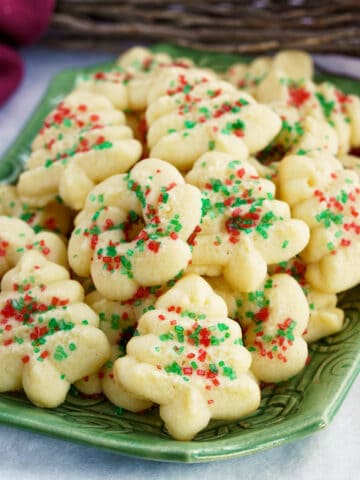 A stack full of tender cream cheese spritz cookies on a square dish.