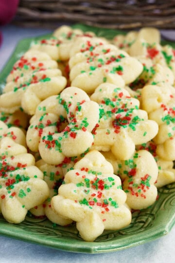A stack full of tender cream cheese spritz cookies on a square dish.