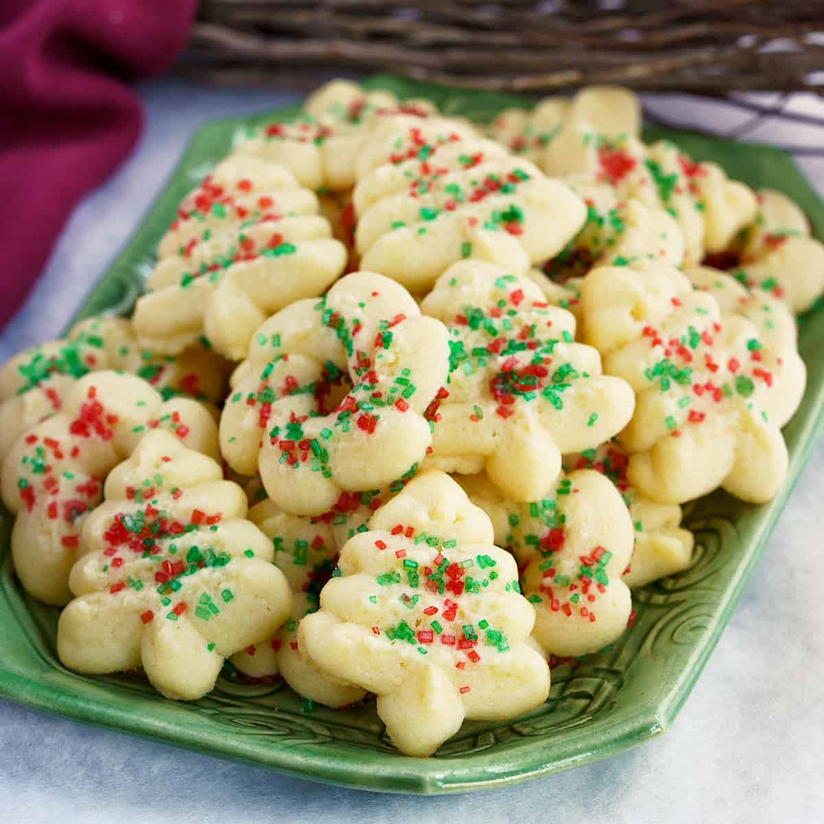 A stack full of tender cream cheese spritz cookies on a square dish.