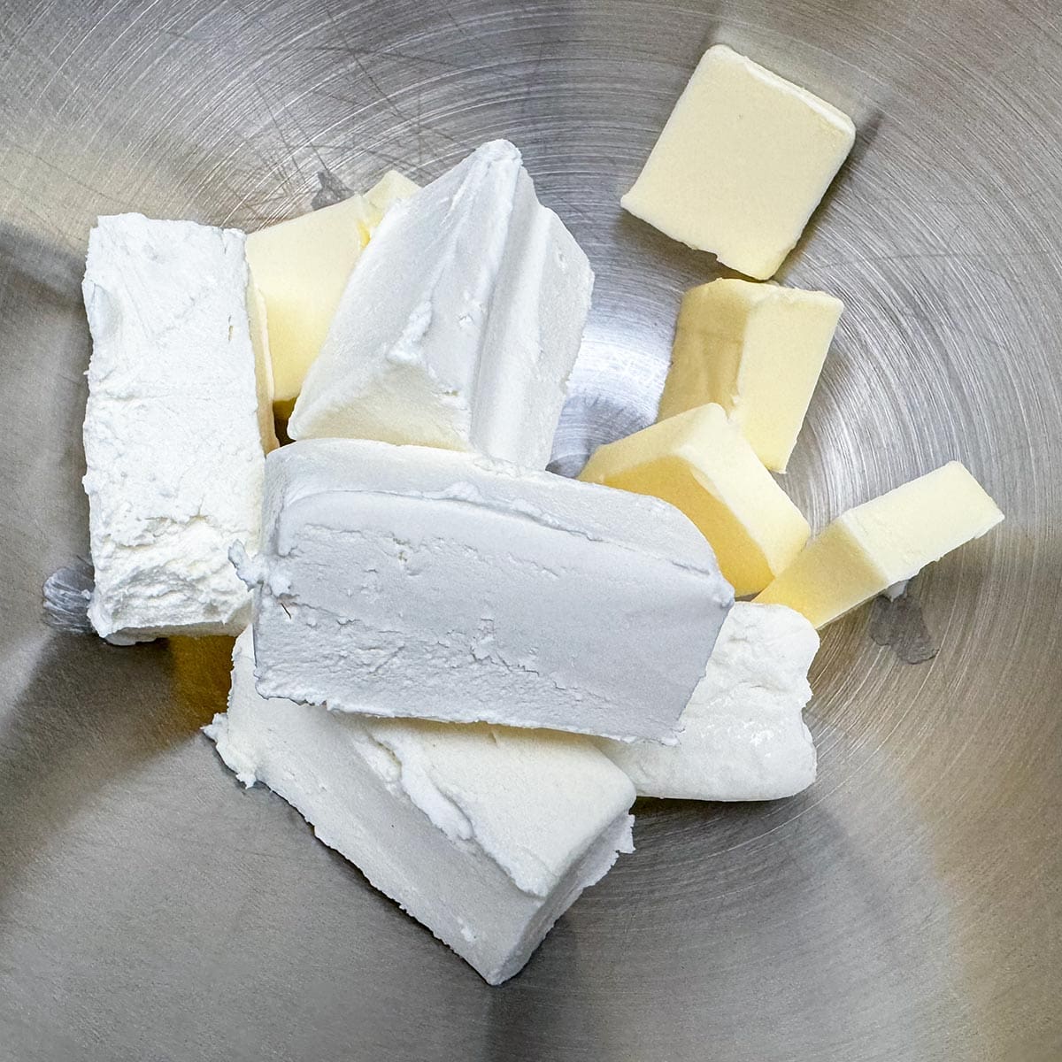 Cubes and slices of butter and cream cheese are getting ready to be mixed.