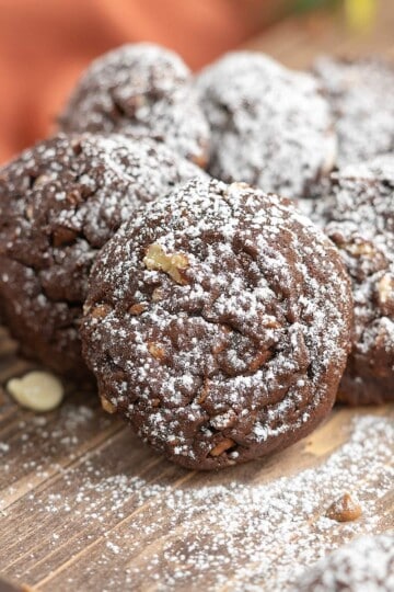 White Chocolate and caramel chocolate cookies on a wooden board sprinkled with powder sugar on top.