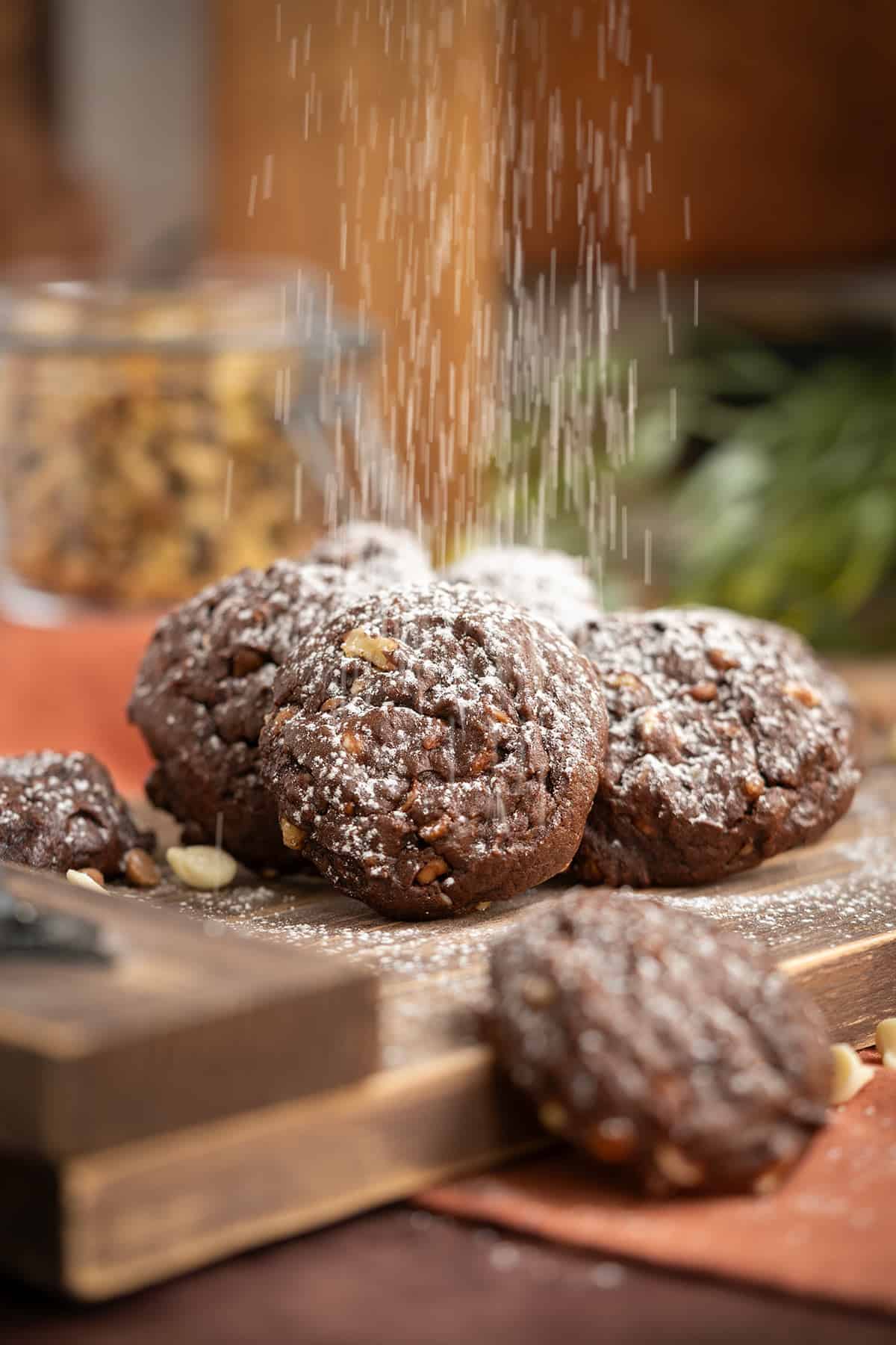 A shower of powdered sugar on top of a stack of white chocolate and caramel chocolate cookies.