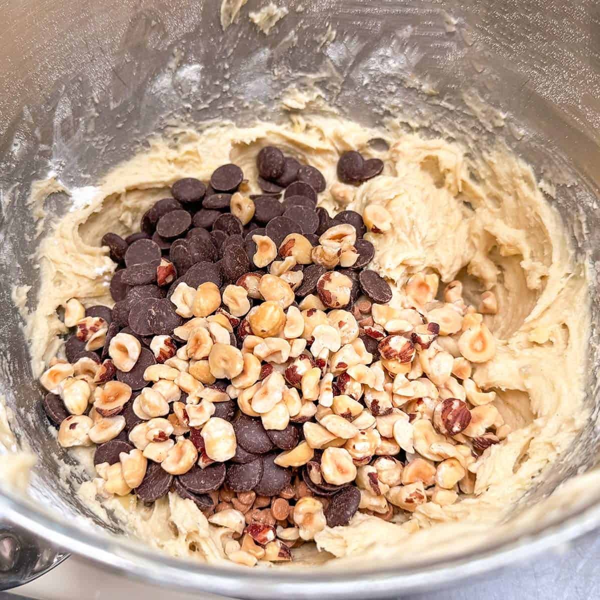 Adding the chocolate and caramel chips along with the chopped hazelnuts to the cookie dough.