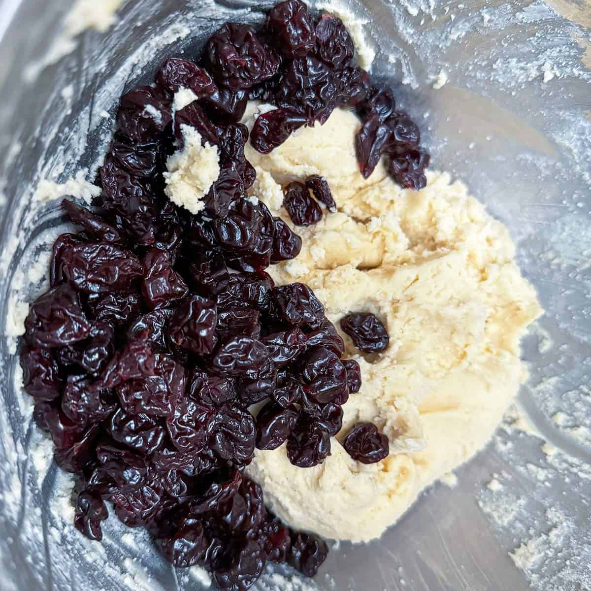 Adding dried cherries to the cookie dough.