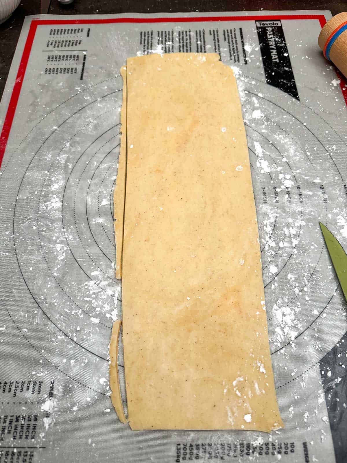 Making the sides of the cookie dough roll by slicing off the excess.