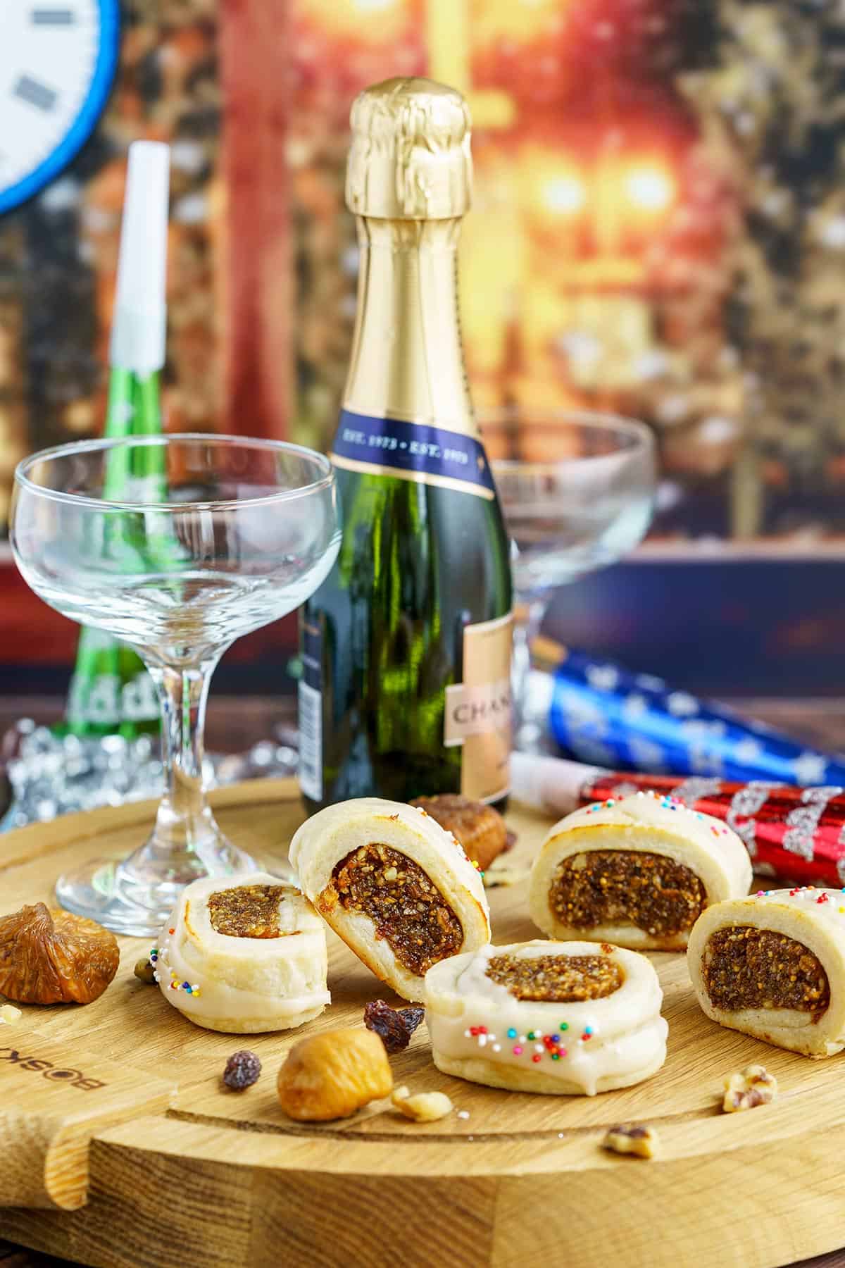 Fig Cookies with Vanilla Glaze on a wooden board with champagne glasses and New Years decorations.