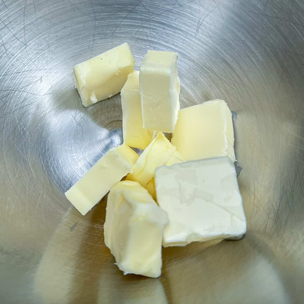 Butter that has been cut into cubes sitting in a mixer bowl.