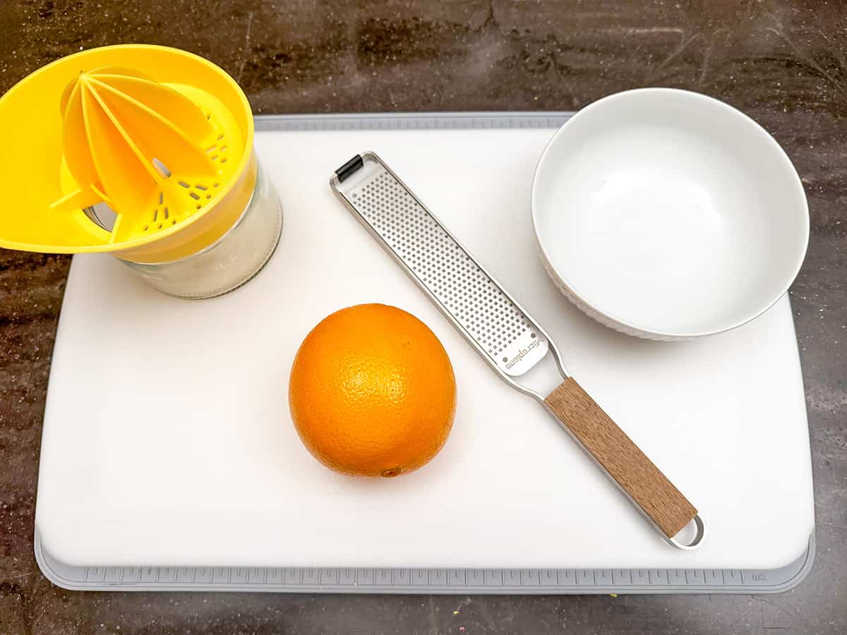 Equipment to juice and zest an orange. You need a small bowl, zester, and juicer.