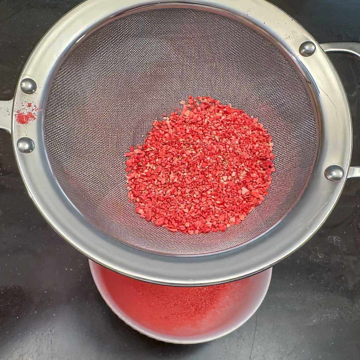 Sifting large pieces of freeze-dried strawberries after running it through a food processor.