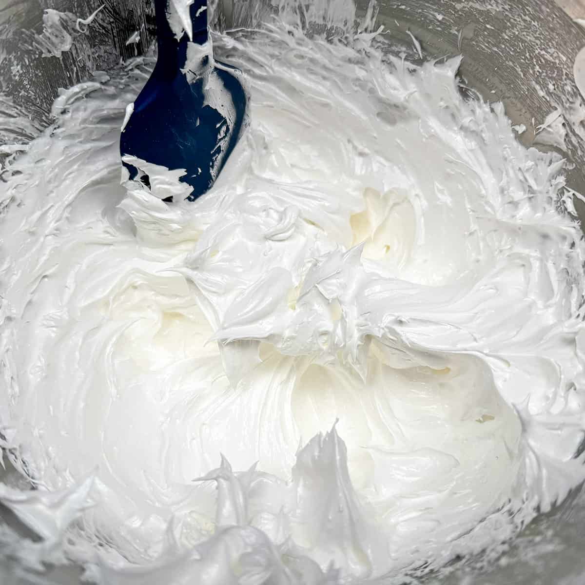 Meringue is in a mixer bowl, is shiny, and has stiff peaks.