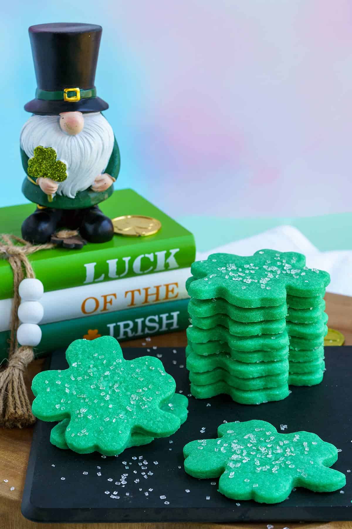 Irish Shamrock Sugar Cookies with a leprechaun standing on a stack of books.