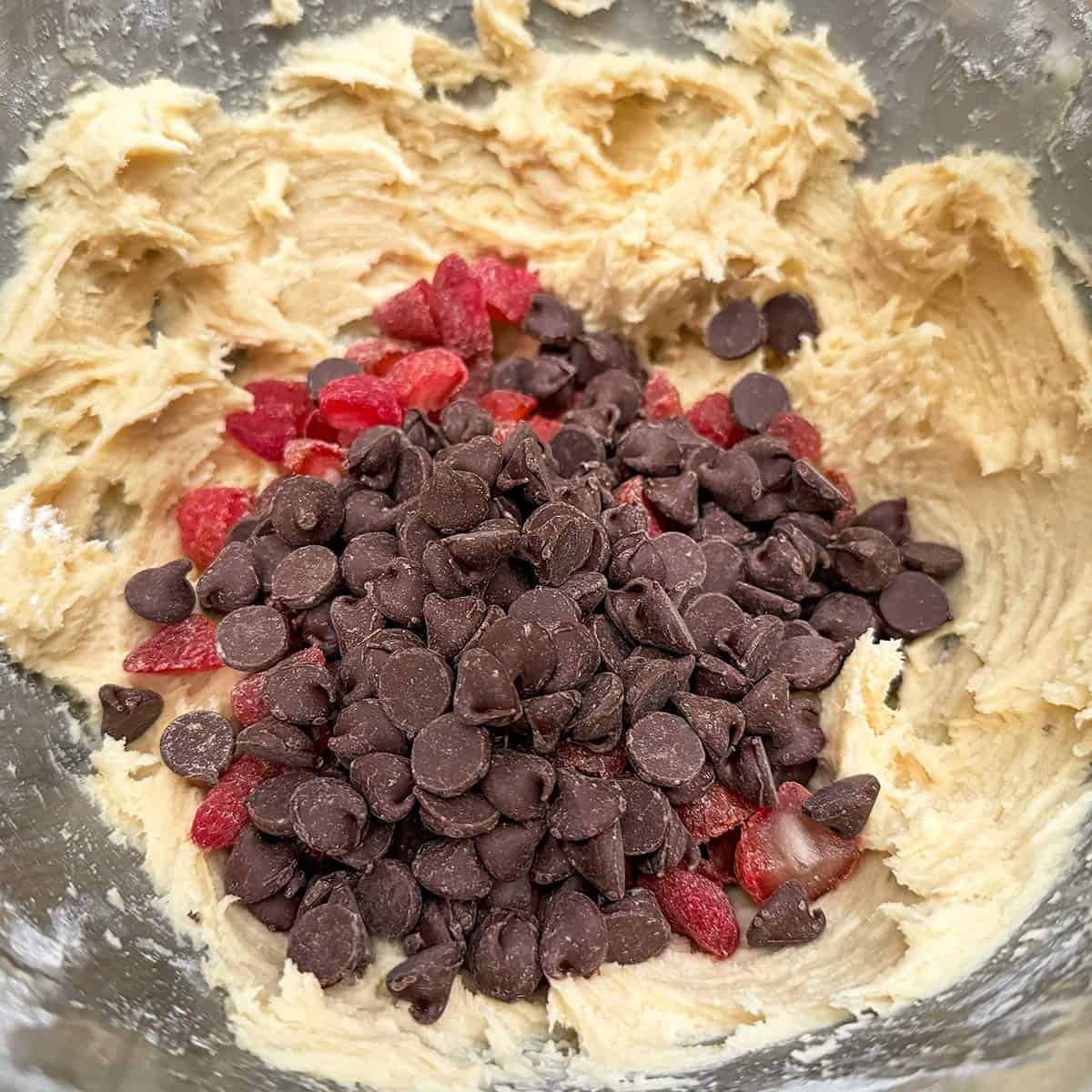 Adding chocolate chips and strawberries to the cookie dough.