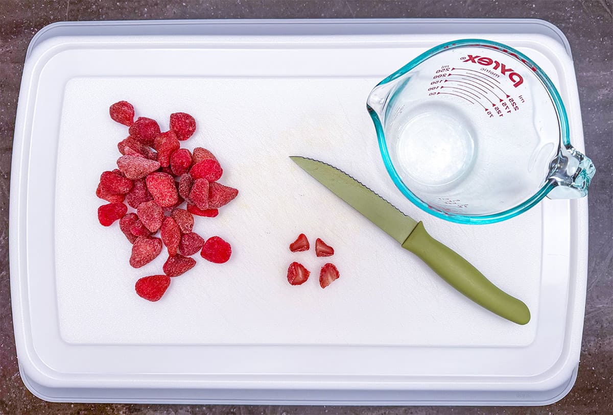Cutting up dried strawberries into small pieces.