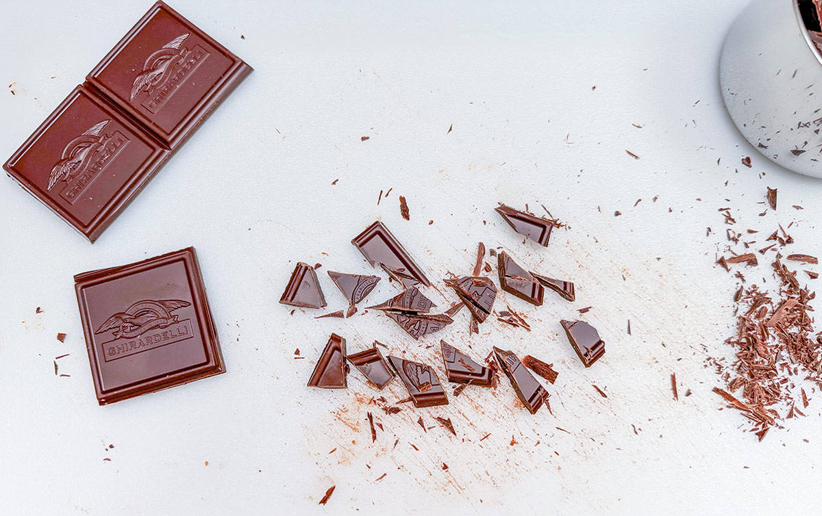 Cutting the chocolate squares into small chunks on a cutting board.