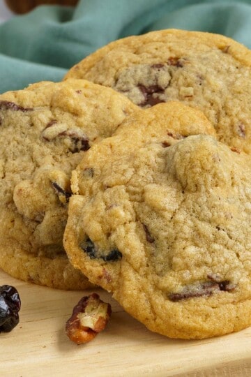 Baked chunky chocolate with cherry and pecan cookies on a wooden plank.