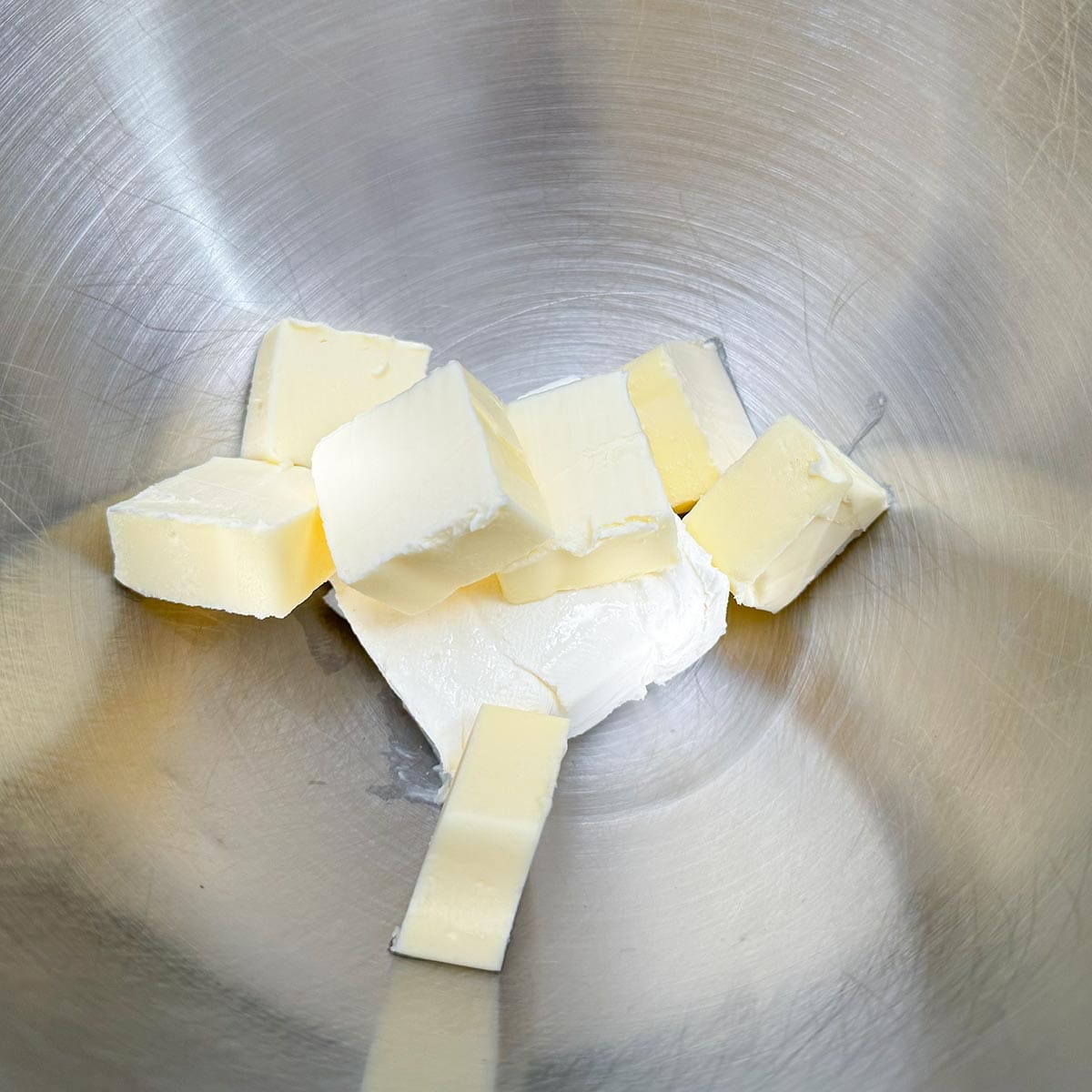 Cubed butter and cream cheese in a mixer bowl.
