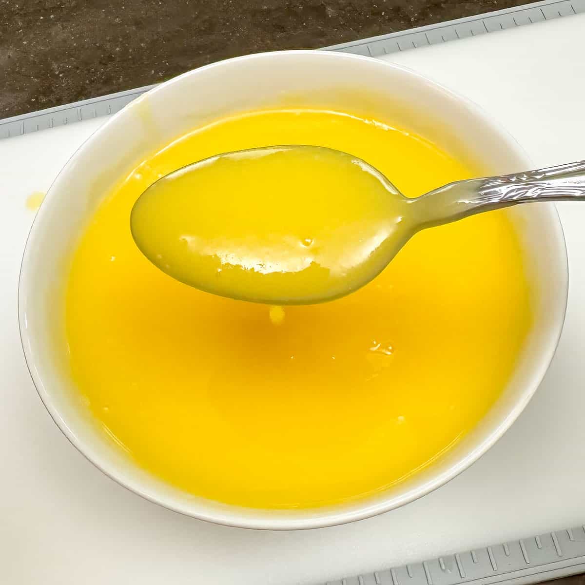 Smooth lemon curd after it has been strained in a small bowl.