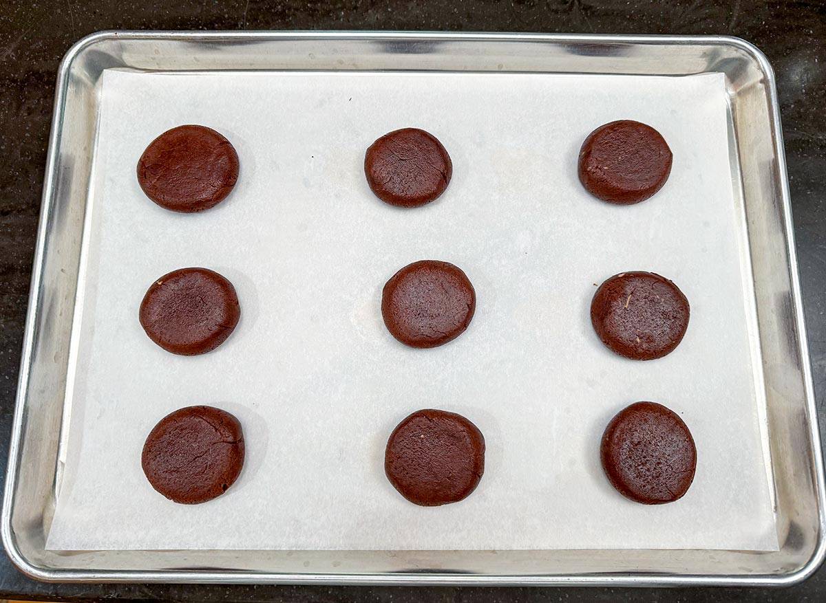 Nine cookies on a sheet pan ready for the oven.