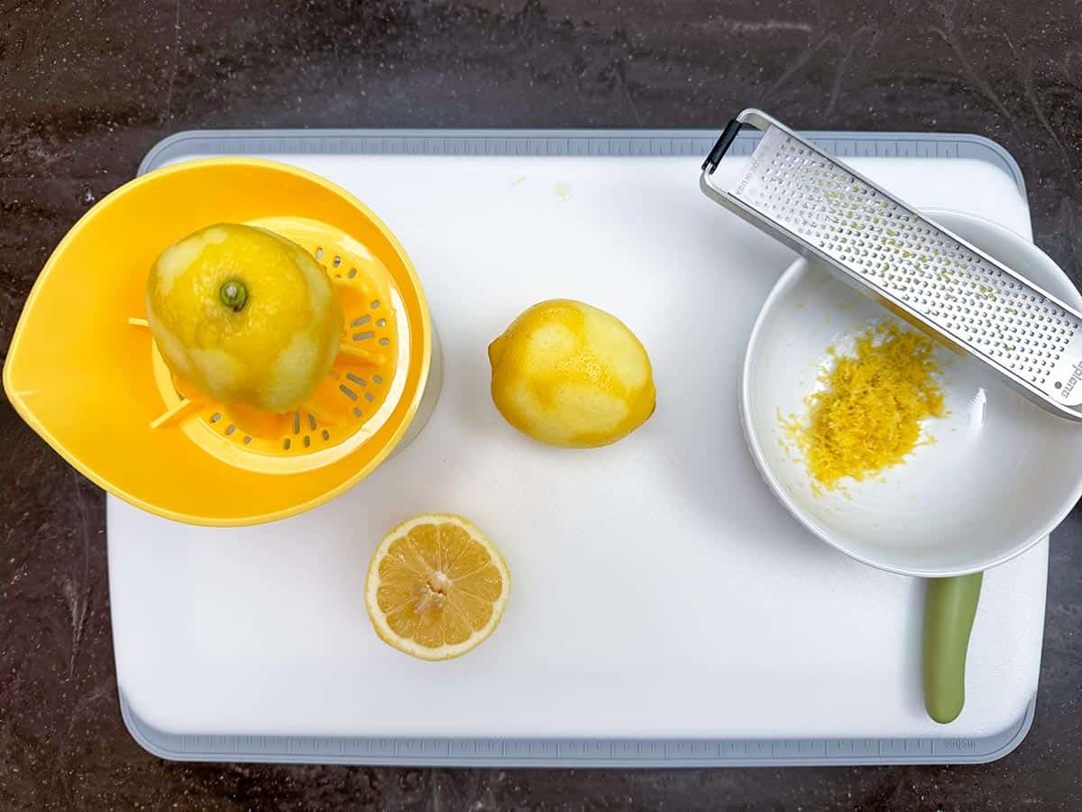 Zesting and juicing lemons on a cutting board.