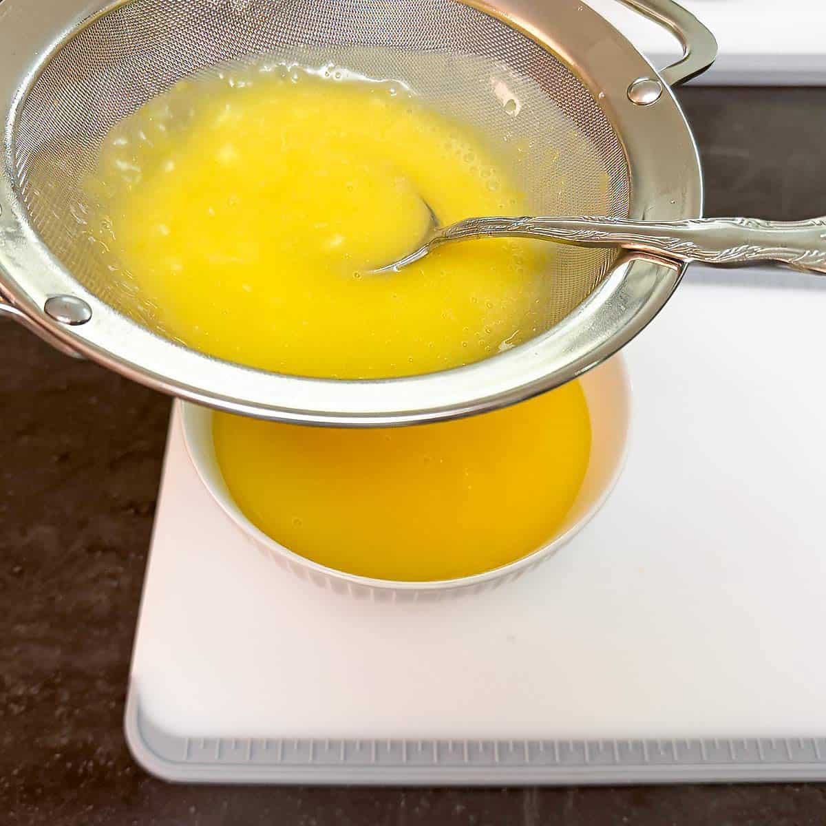 Straining the cooked lemon curd into a bowl.