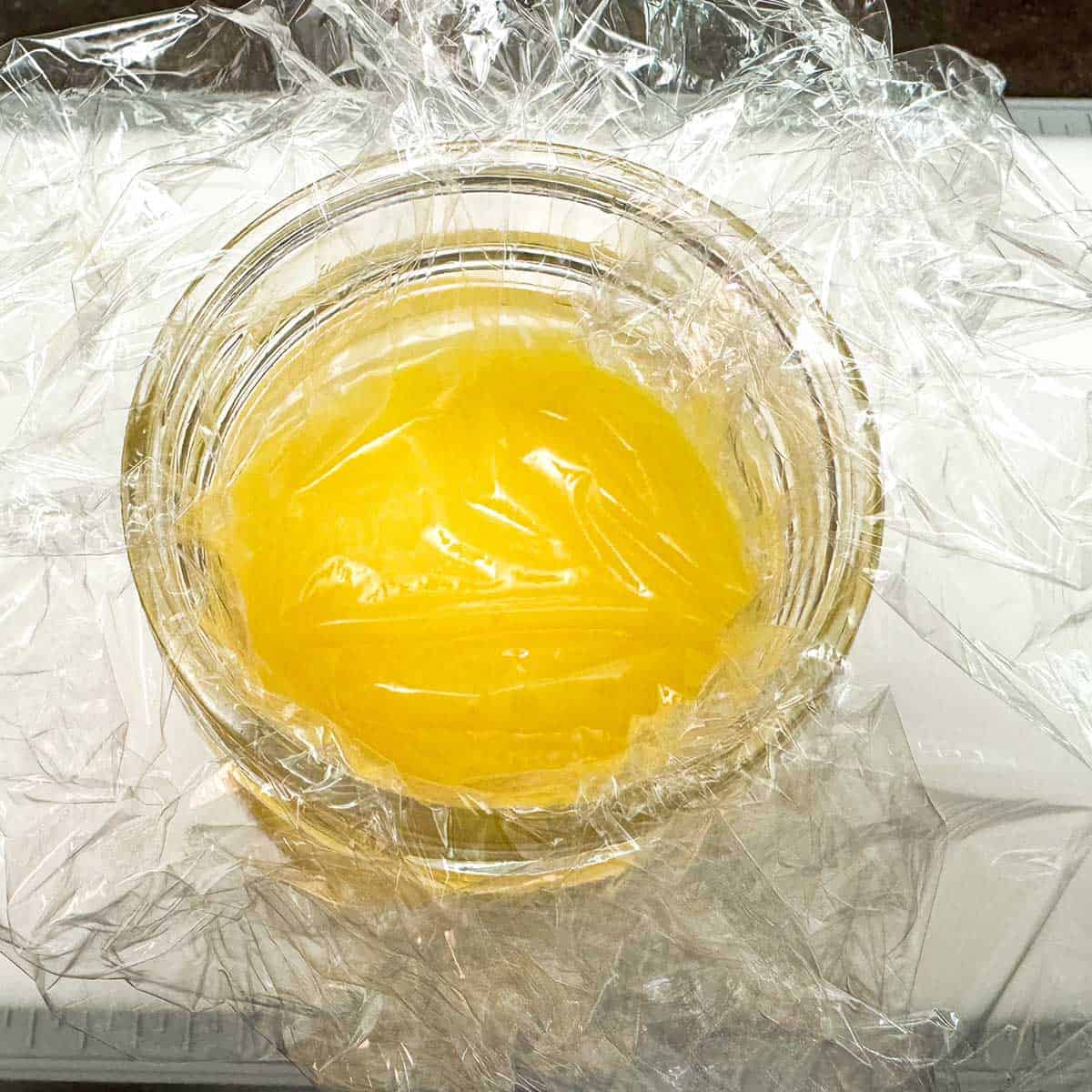 Lemon curd with plastic wrapped on top of the curd to prevent crusting.