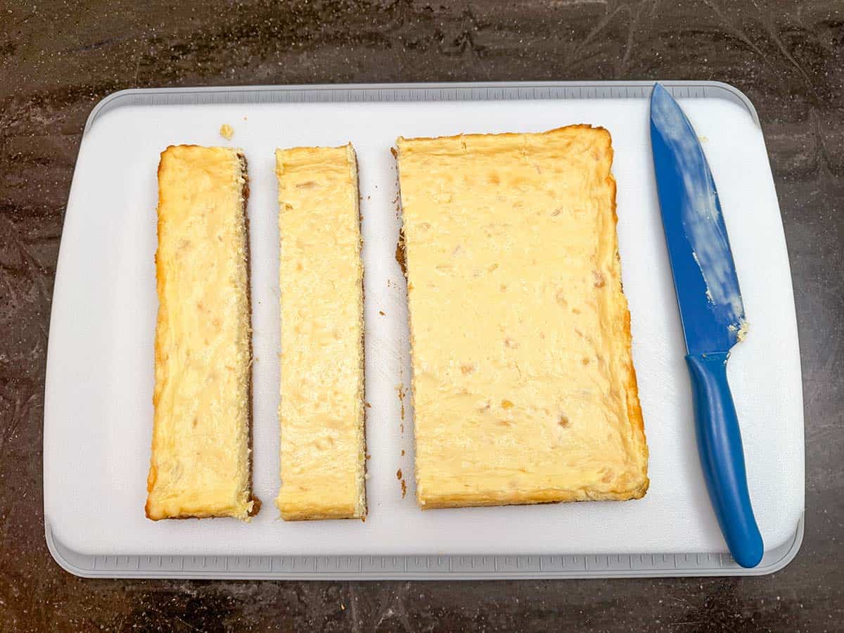 Baked pineapple cheesecake bites being cut into squares.