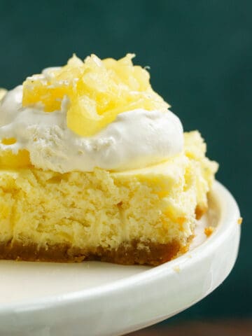 Side view of the pineapple cheesecake bite with whip cream and pineapple on top.