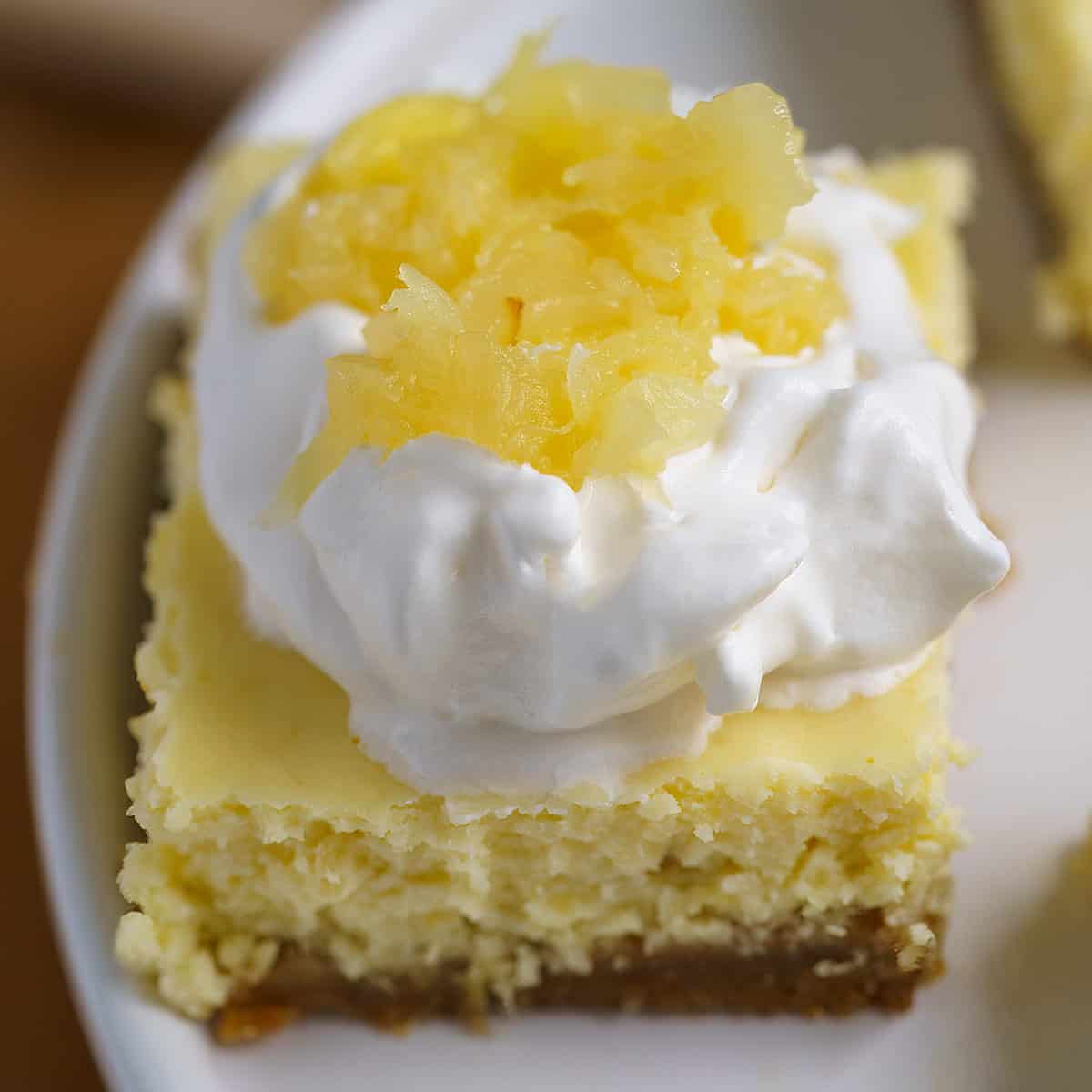 Top view of the pineapple cheesecake bite with whip cream and pineapple on top.
