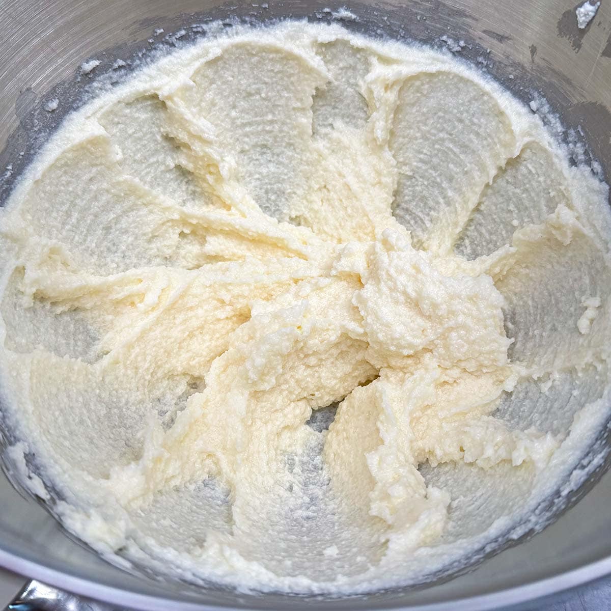 Ricotta cheese added to the butter-sugar mixture, looking a little lumpy.