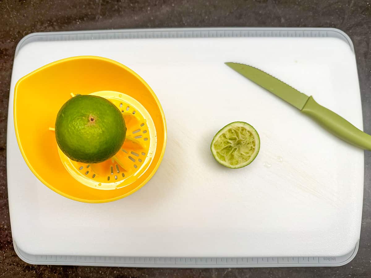 Juice a lime into a juicer container on a cutting board.