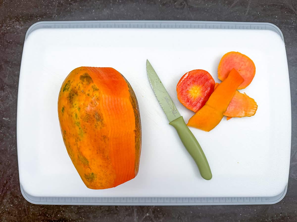 Peeling a papaya with a knife.