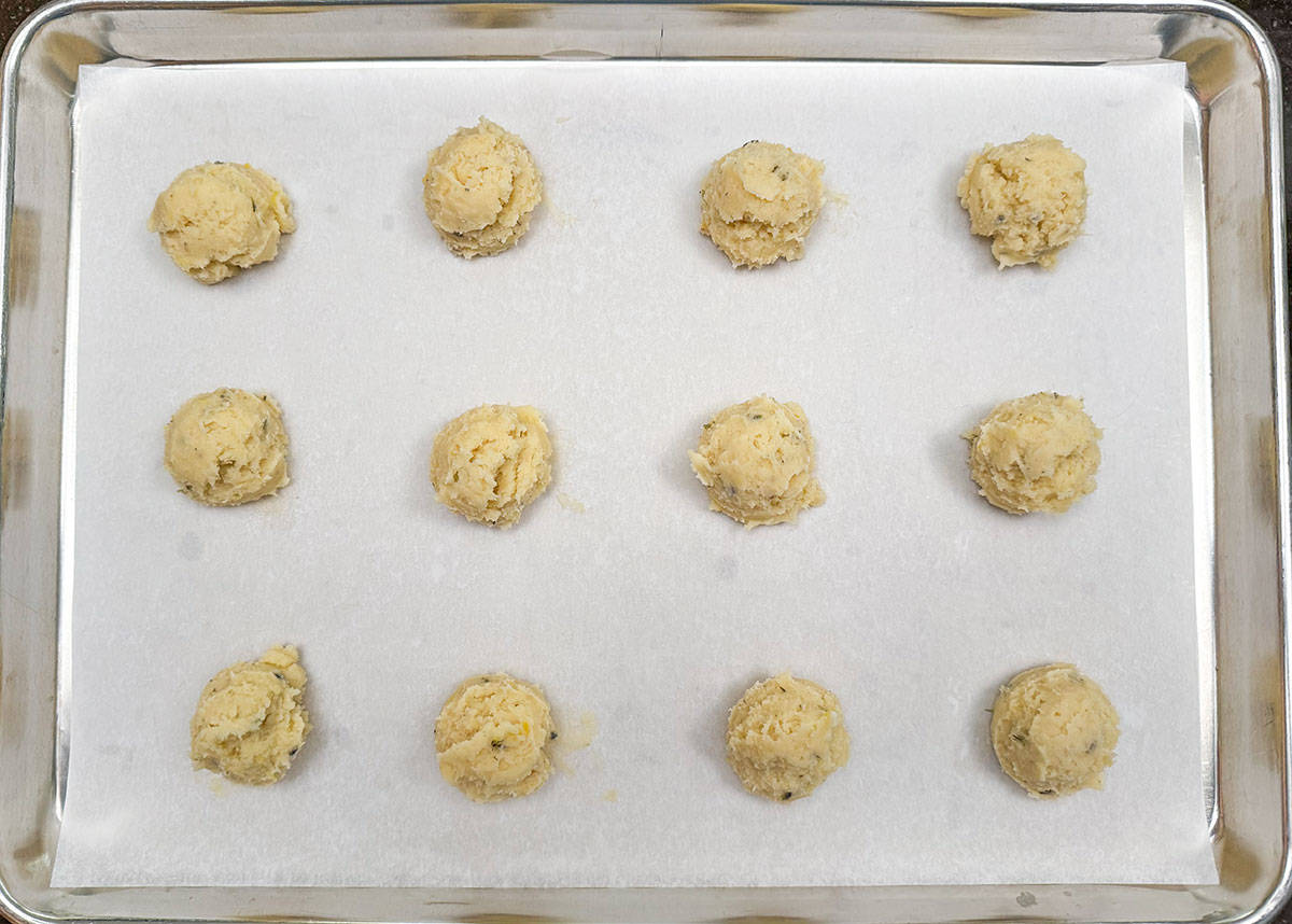 Scooped cookie dough on a parchment-lined sheet pan.