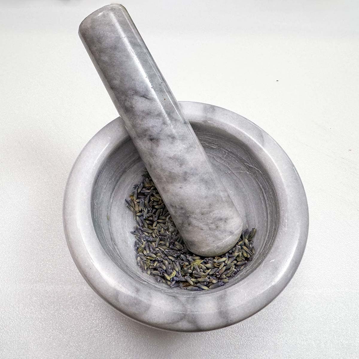 Crushing lavender in a mortar and pestle.