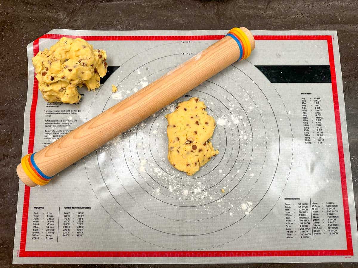 Rooling pin with height ring on the ends with the cookie dough on a pastry mat.
