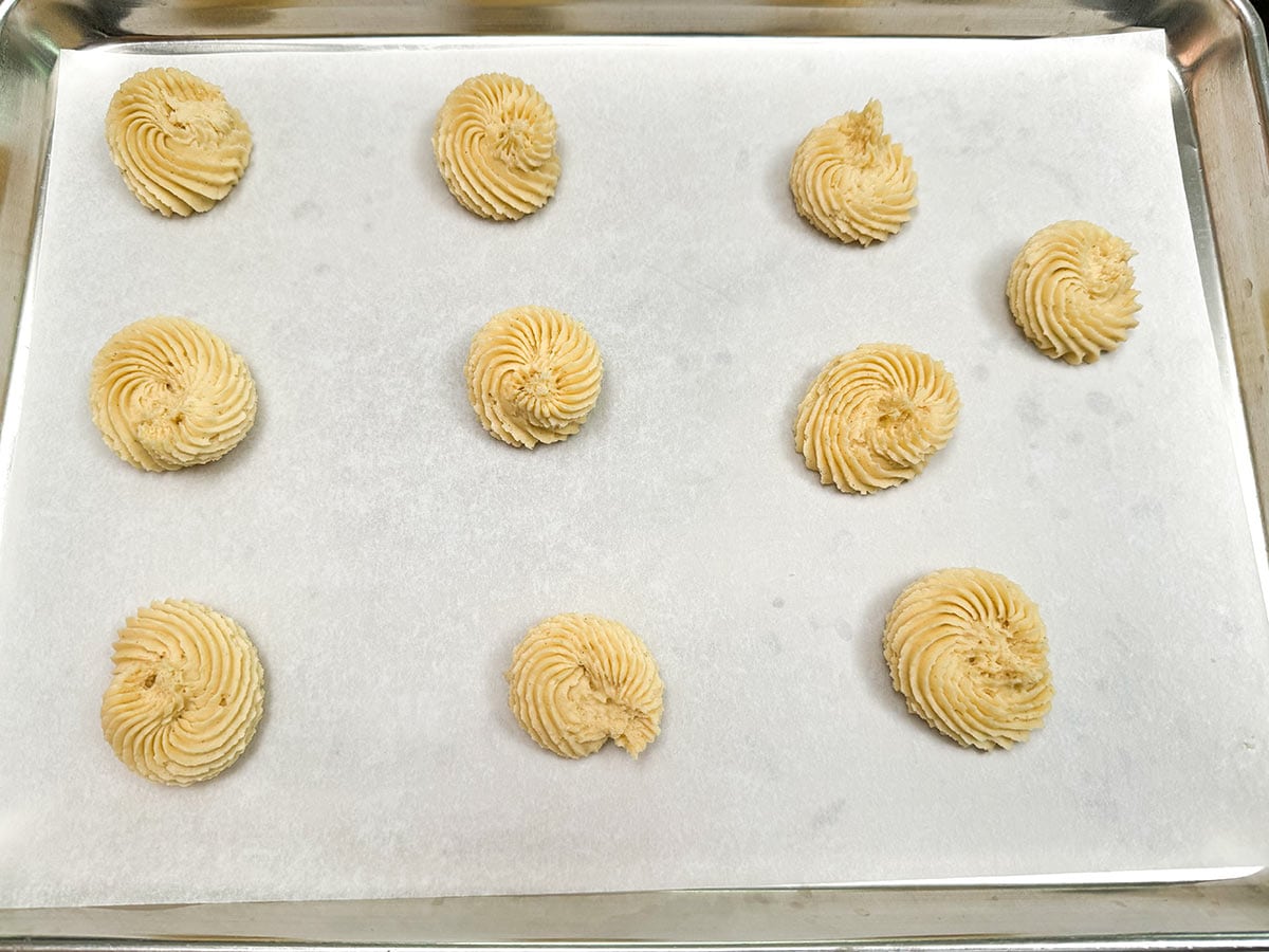 Piped danish butter cookies on a parchment lined sheet pan.