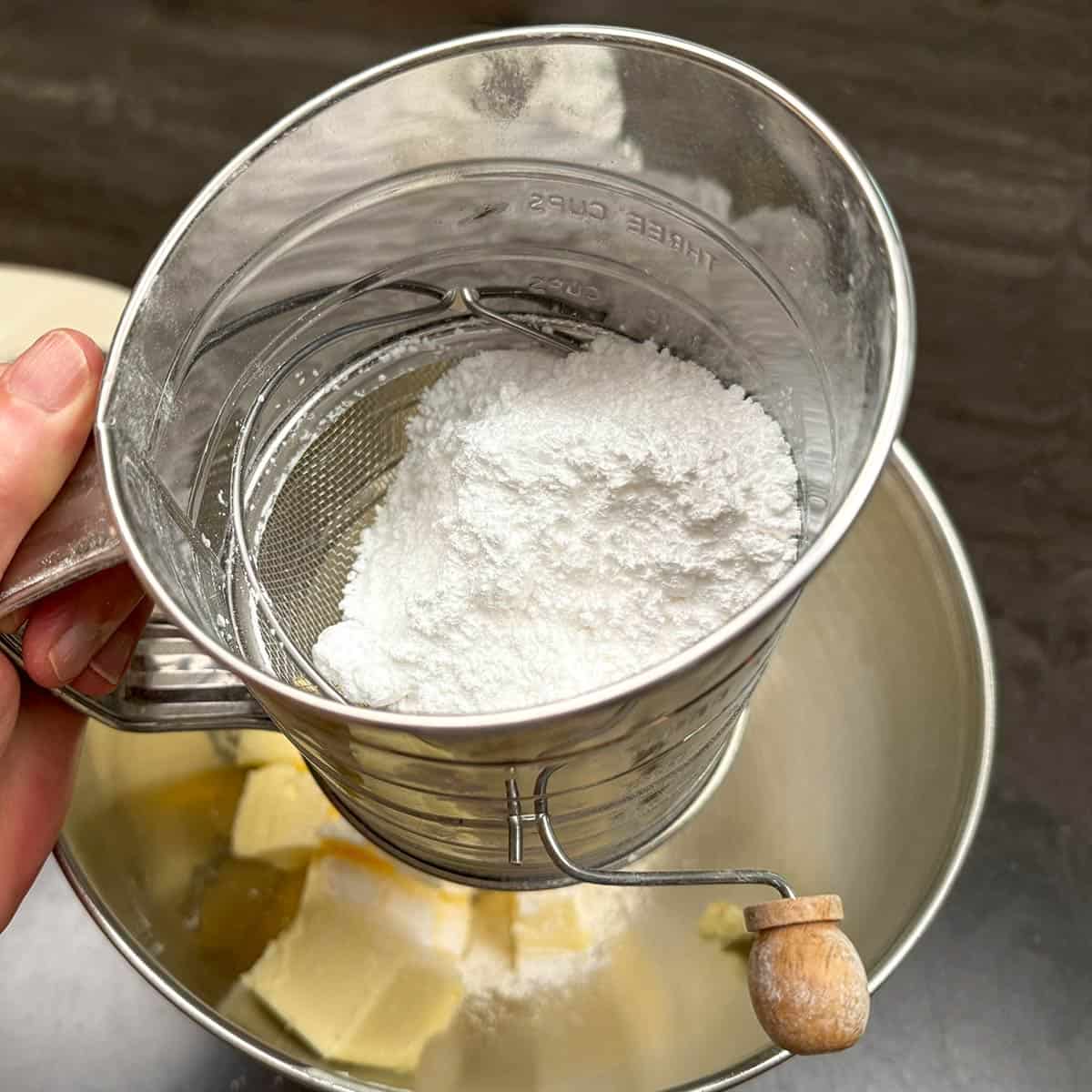 Sifting powdered sugar onto the cubed butter to be mixed.