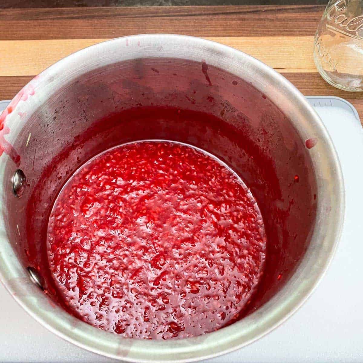 Cooling the raspberry jam in the pan before moving to a glass container.