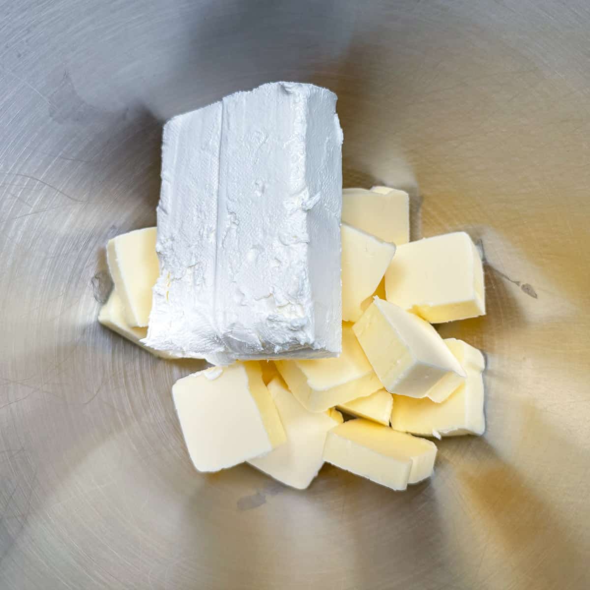 Cubed butter and cream cheese block in the mixer bowl.