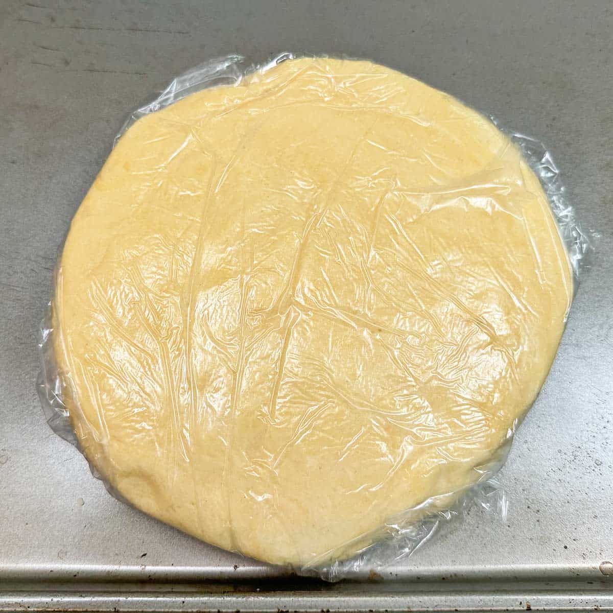 Cookie cup dough flattened and wrapped in plastic wrap for chilling.