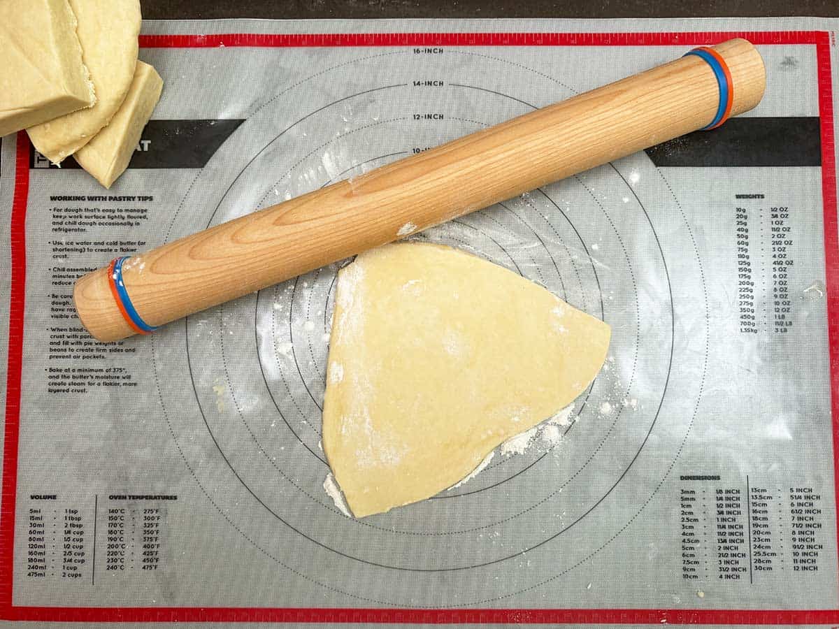 Showing pastry mat with the rolling pin starting to roll out cookie dough.