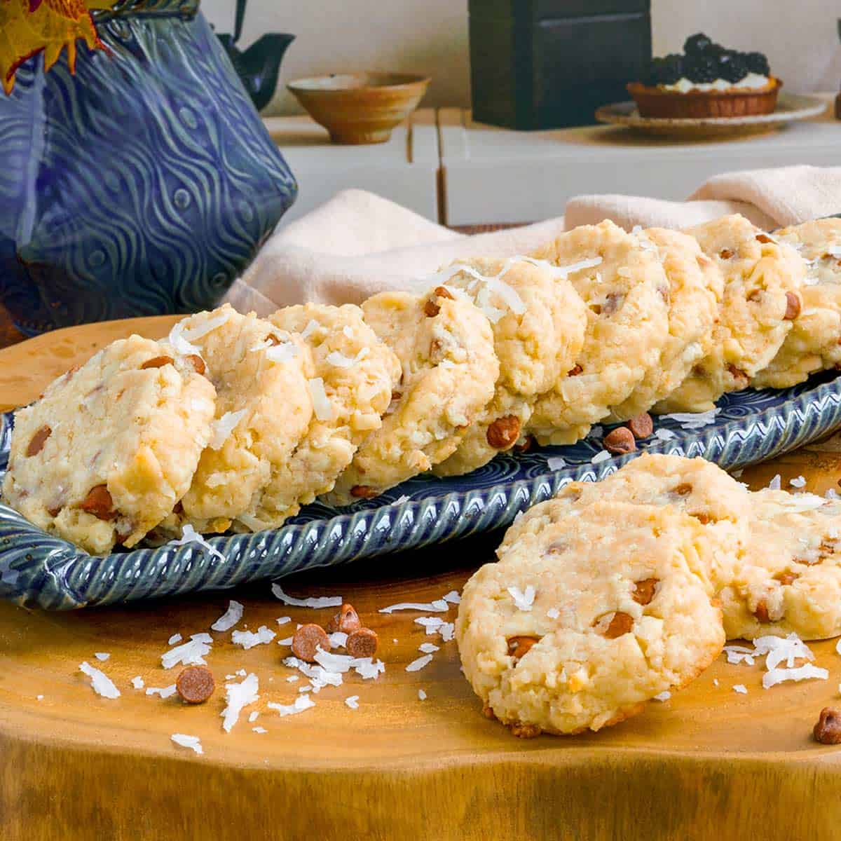 Cinnamon chips with coconut and almonds cookies on a narrow dish with a few on the wooden board.