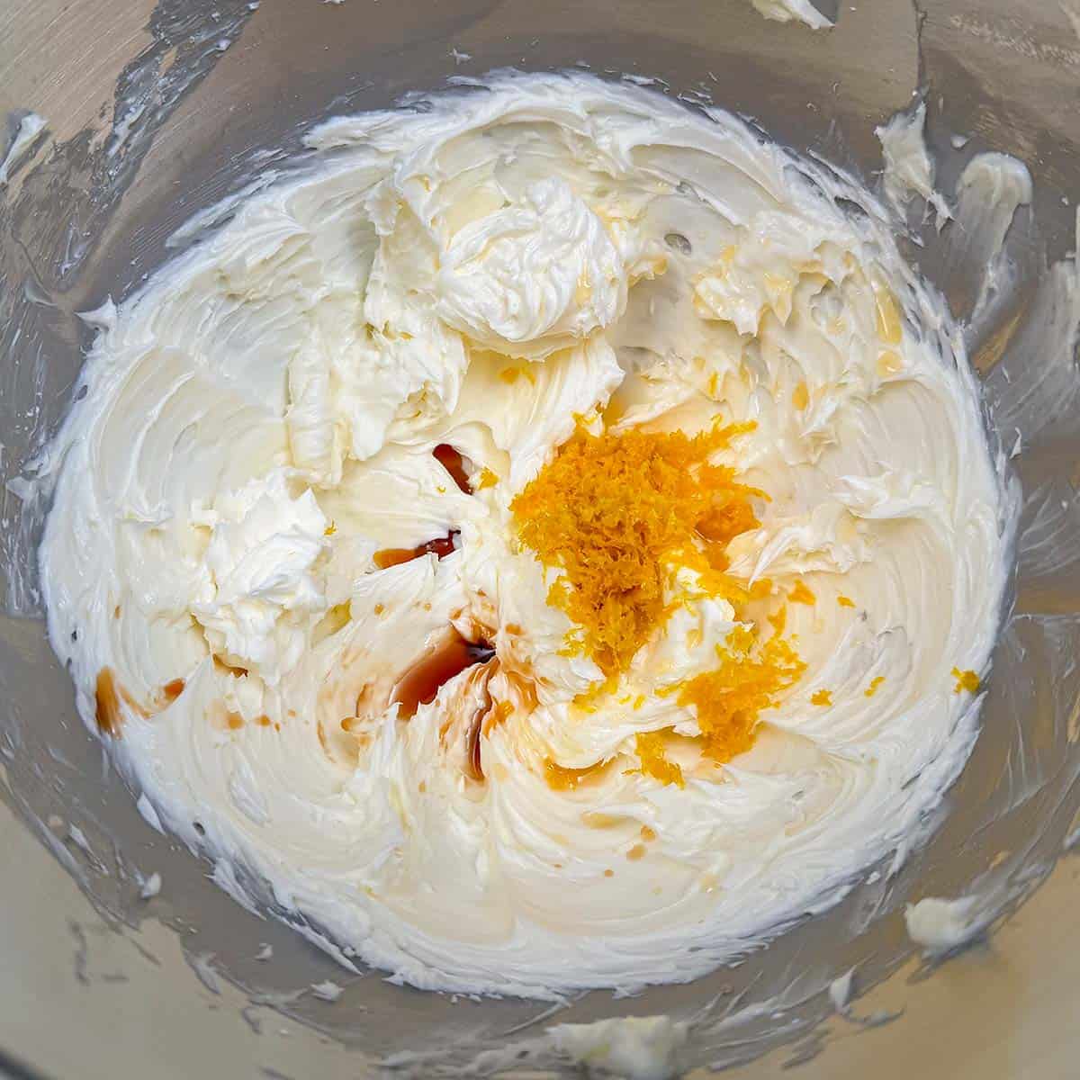 Adding orange zest, juice, and vanilla extract to the butter sugar mixture.